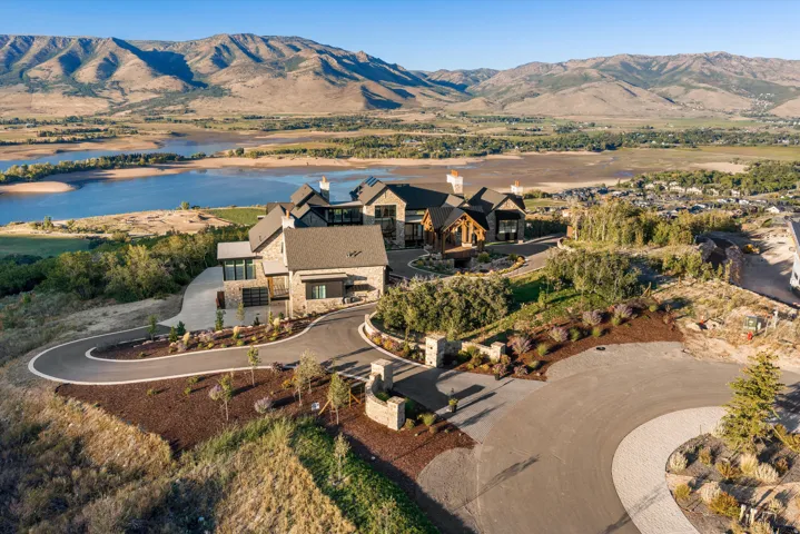 Expansive property featuring a stone and wood facade, a paved circular driveway, and mature landscaping