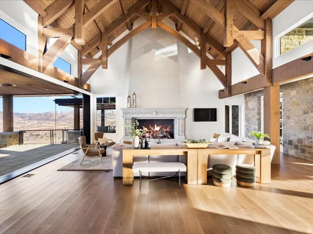Living room with a large fireplace, a mountain view, a high wooden beamed ceiling, and hardwood / wood-style flooring