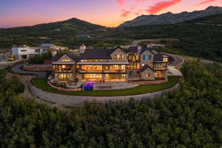 Stone exterior with expansive windows, multiple balconies, and a built-in outdoor pool