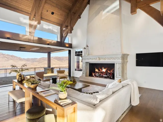 Living area with a high end fireplace, hardwood / wood-style floors, and a high wood beamed ceiling