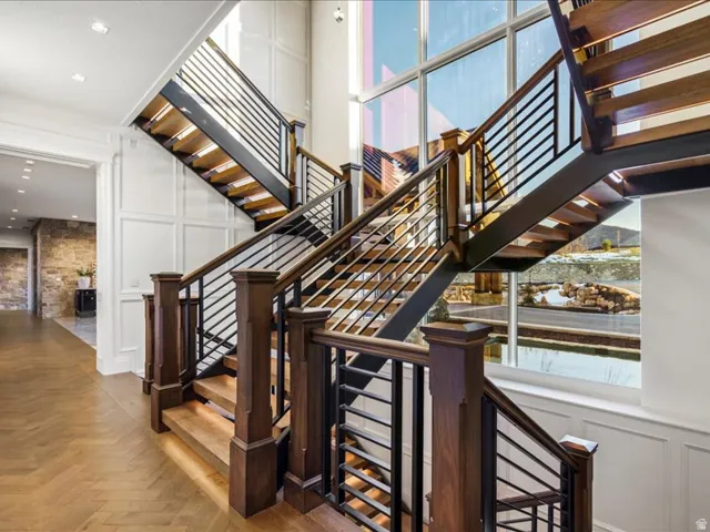 Staircase featuring a decorative wall, parquet flooring, and a high ceiling