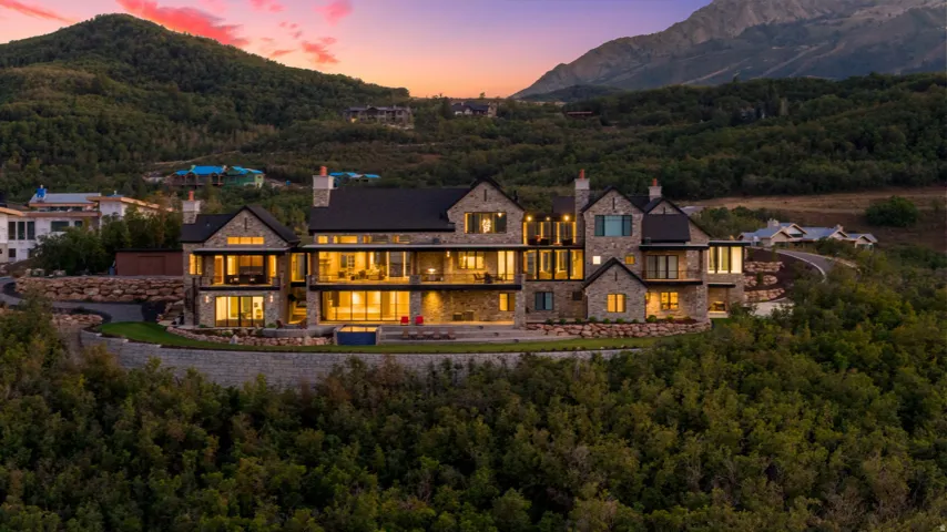 Stone-clad exterior, multi-level design, extensive balconies, large windows, and surrounding natural landscaping