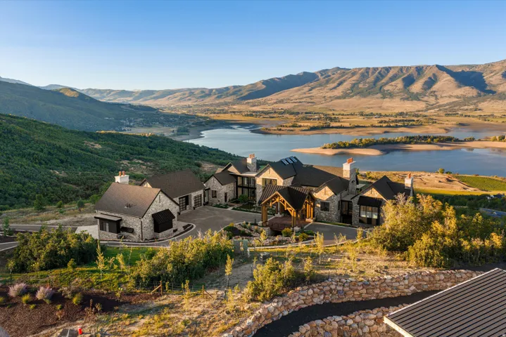 Stone exterior residence with multiple chimneys, a prominent wood-clad entry, and an attached garage structure