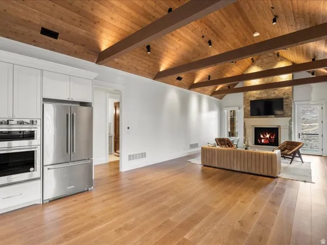 Living room with a high wooden beamed ceiling, light wood finished floors, and a fireplace