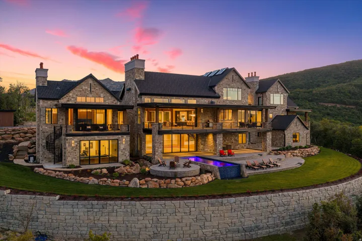 Stone exterior with multiple balconies, an infinity-edge pool, and an integrated spa
