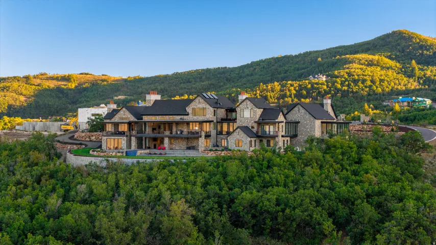 Stone-clad exterior with multiple balconies, dark roof, and extensive natural landscaping