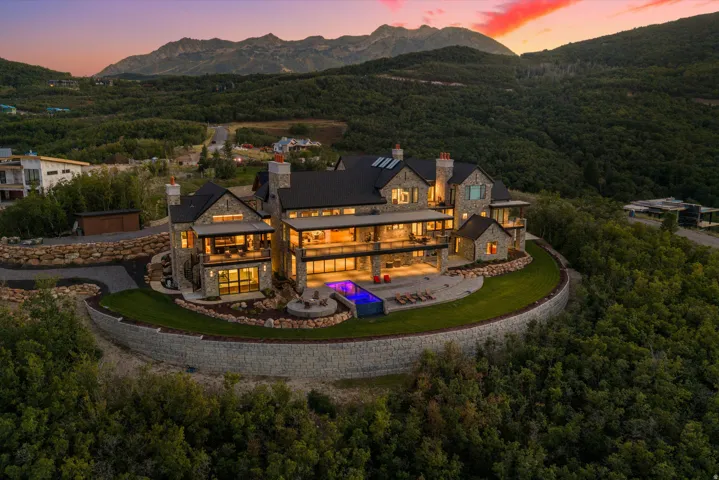 Stone-clad exterior, tiered retaining walls, multi-level balconies, expansive glass panels, and a built-in outdoor pool