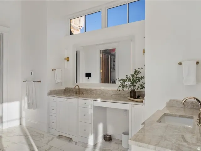 Bathroom with vanity, a high ceiling, and light marble finish flooring