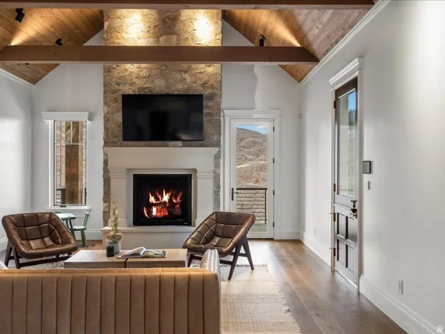 Living room featuring a fireplace, a high wooden beamed ceiling, and wood-type flooring