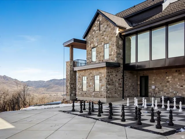 Rear view of house with a mountain view, stone siding, and a patio