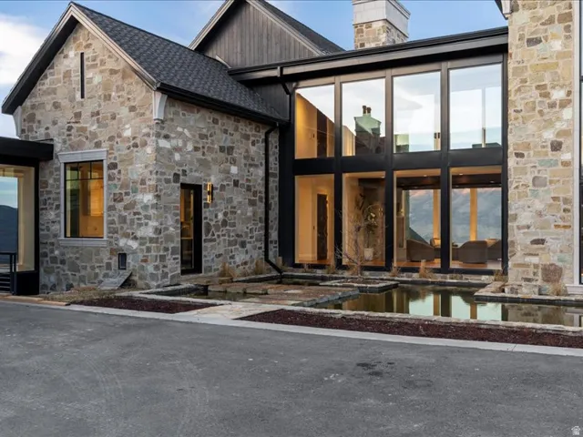 View of exterior entry featuring stone siding, a chimney, an outdoor pool, and a patio area