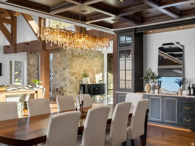 Dining room featuring coffered ceiling, dark wood-style flooring, suspended lighting, and plenty of natural light