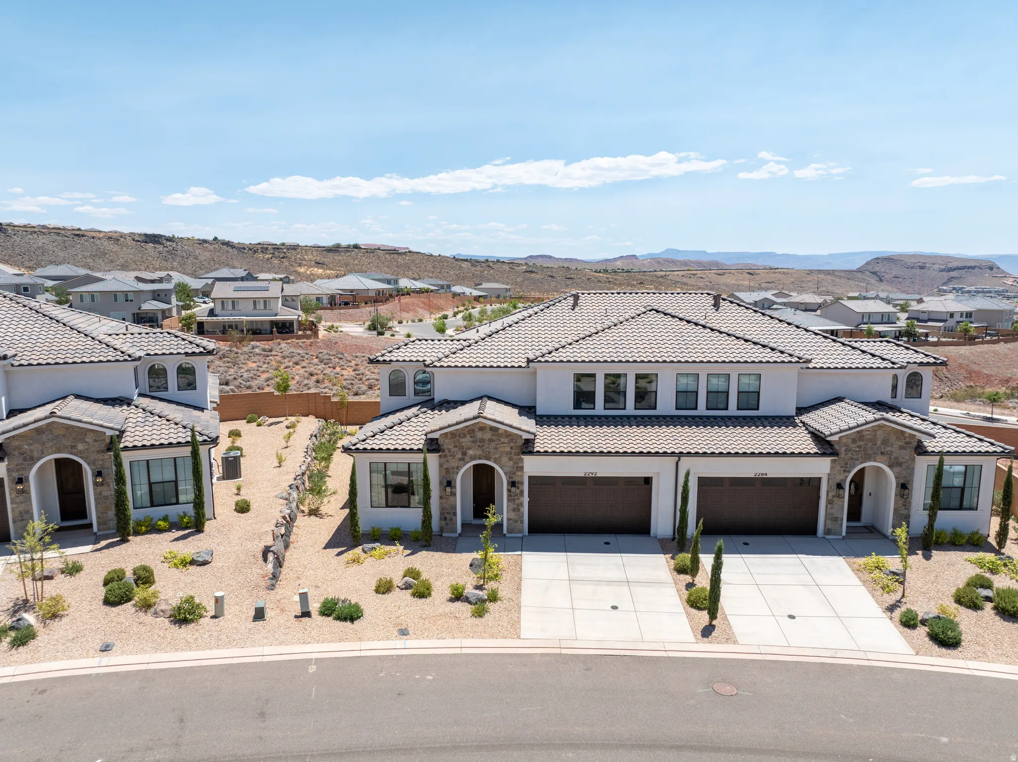 Contemporary duplex residence featuring stucco and stone veneer facades with tile roofs