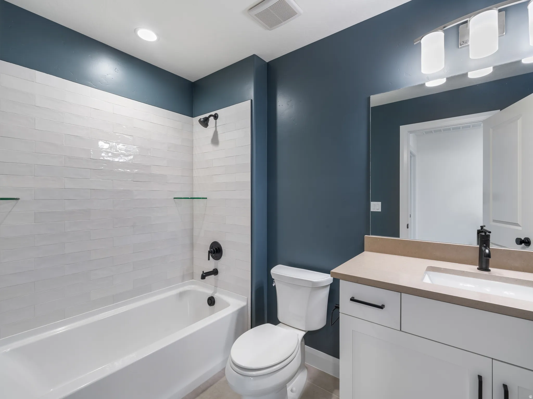 Bathroom featuring a white bathtub, subway tile surround with glass shelves, and matte black fixtures