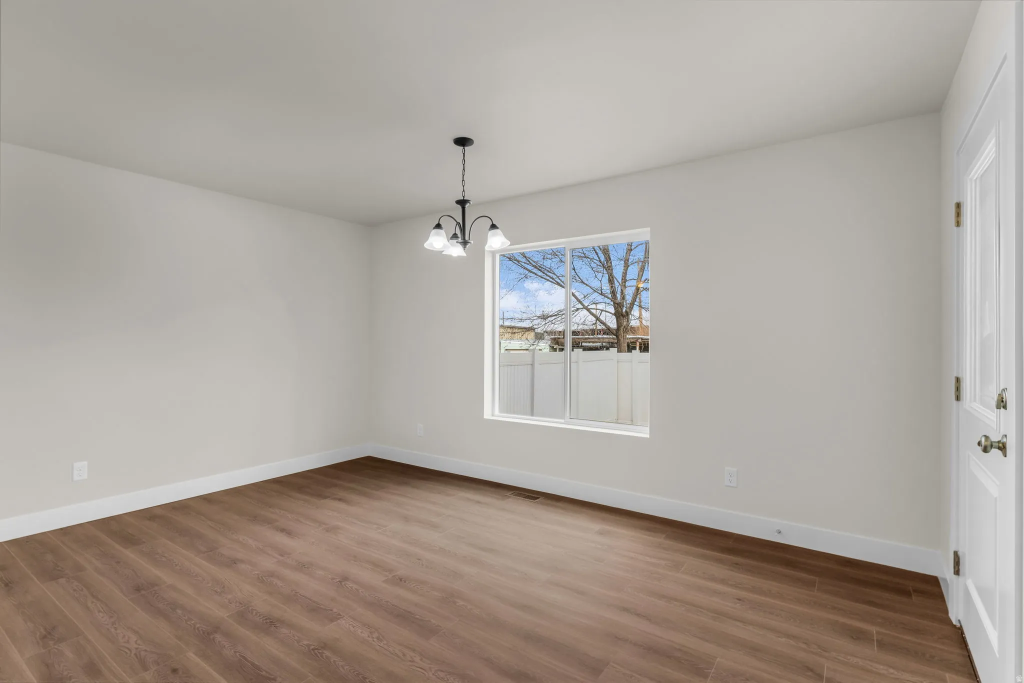 Unfurnished dining area with hanging lights and wood finished floors