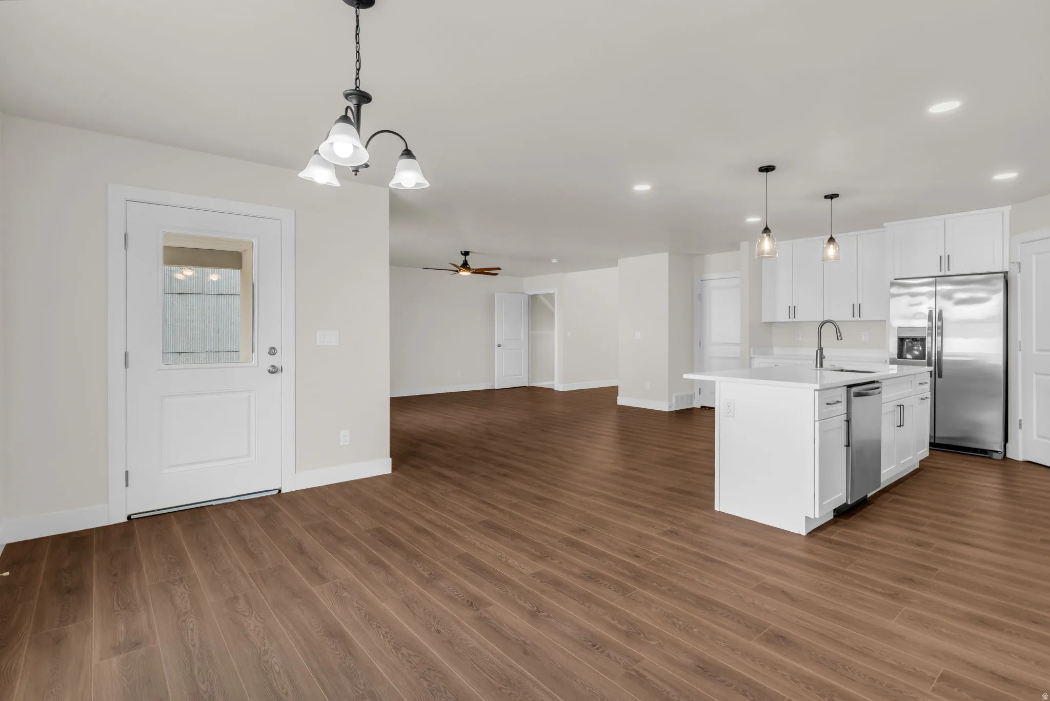 Kitchen with a ceiling fan, open floor plan, a kitchen island with sink, stainless steel appliances, and white cabinets