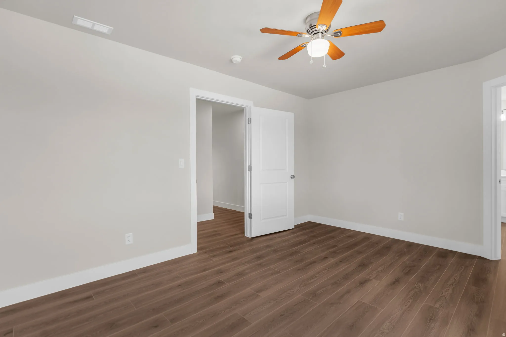 Unfurnished room featuring dark wood-style flooring and ceiling fan