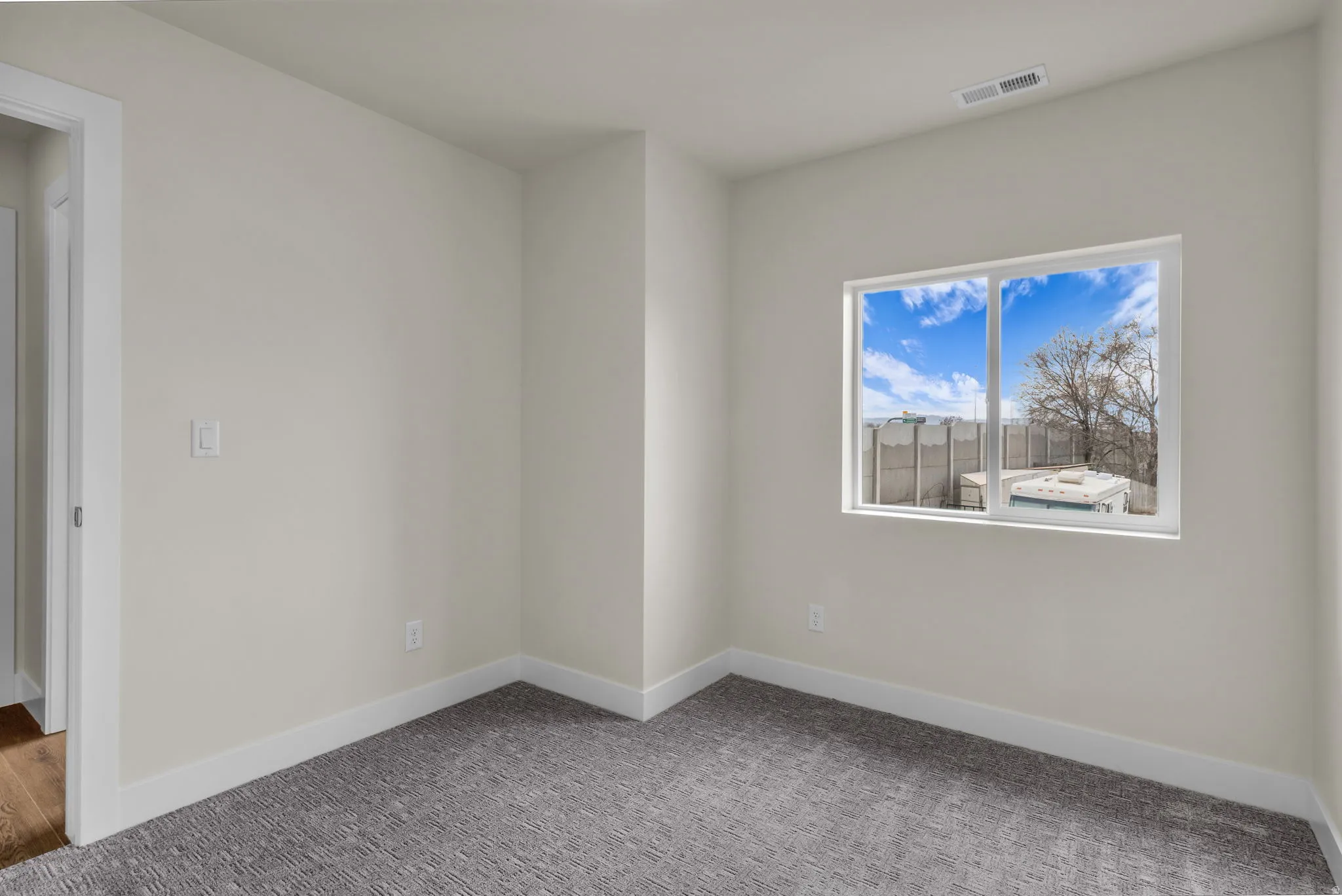 Carpeted spare room featuring baseboards
