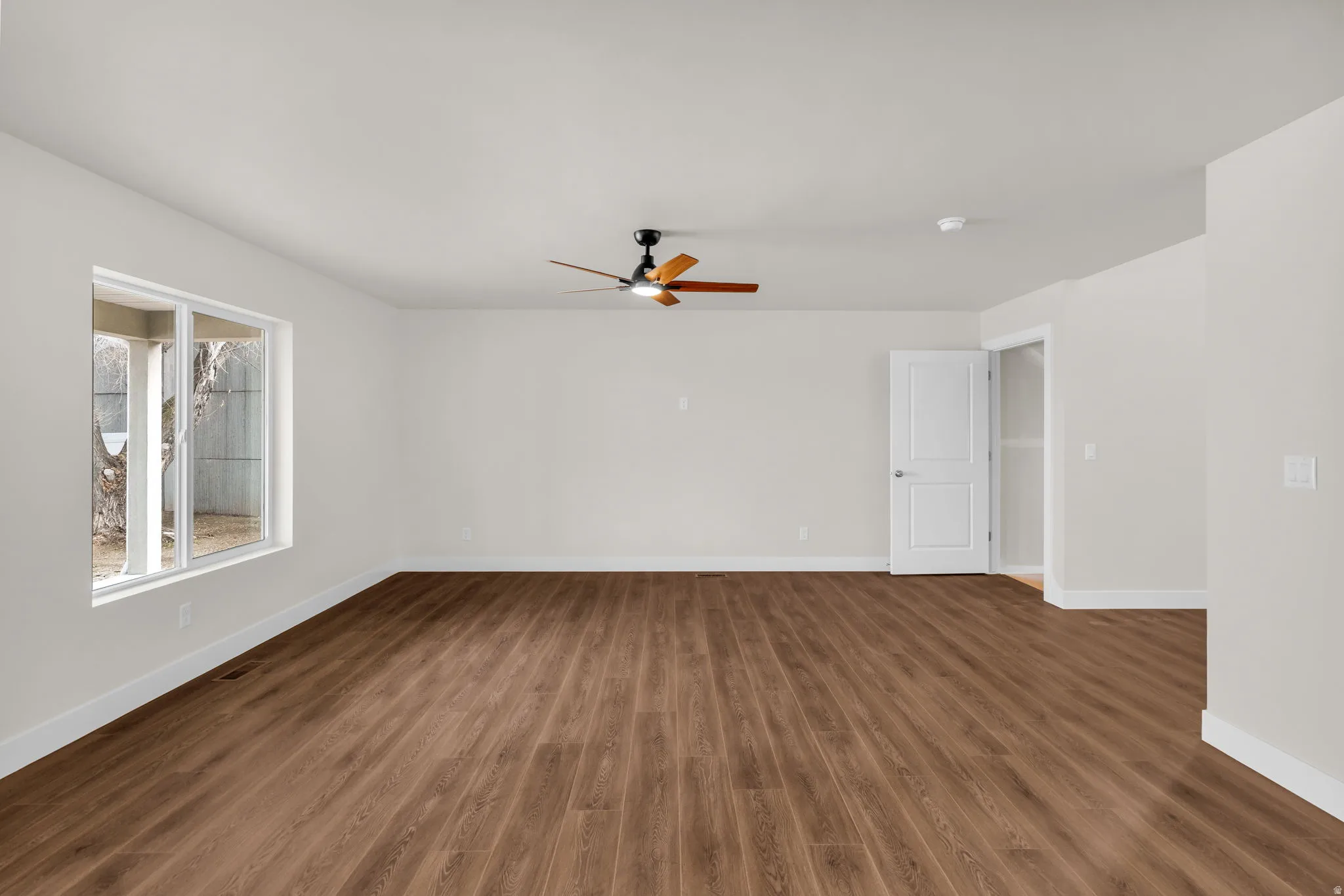 Empty room with dark wood-type flooring and a ceiling fan