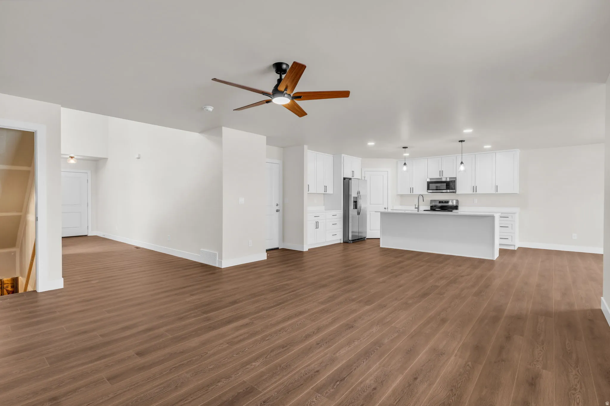 Unfurnished living room featuring a ceiling fan, dark wood-style flooring, and recessed lighting
