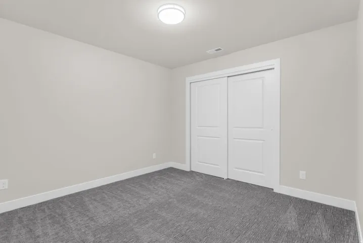 Unfurnished bedroom with dark carpet and a closet