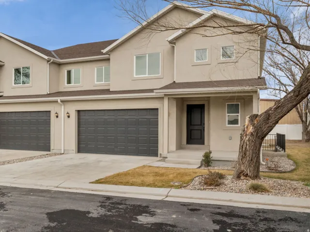 Traditional home featuring covered porch, driveway, stucco siding, and an attached garage