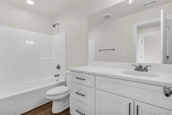 Full bathroom with bathing tub / shower combination, vanity, and dark wood finished floors