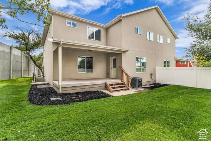 Stucco exterior with multiple windows, covered patio, wooden stairs, and a level lawn area