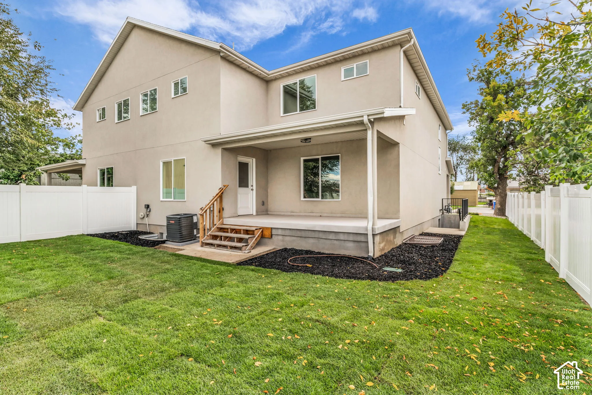 Rear exterior featuring a covered patio, wood stairs, and a white vinyl fence