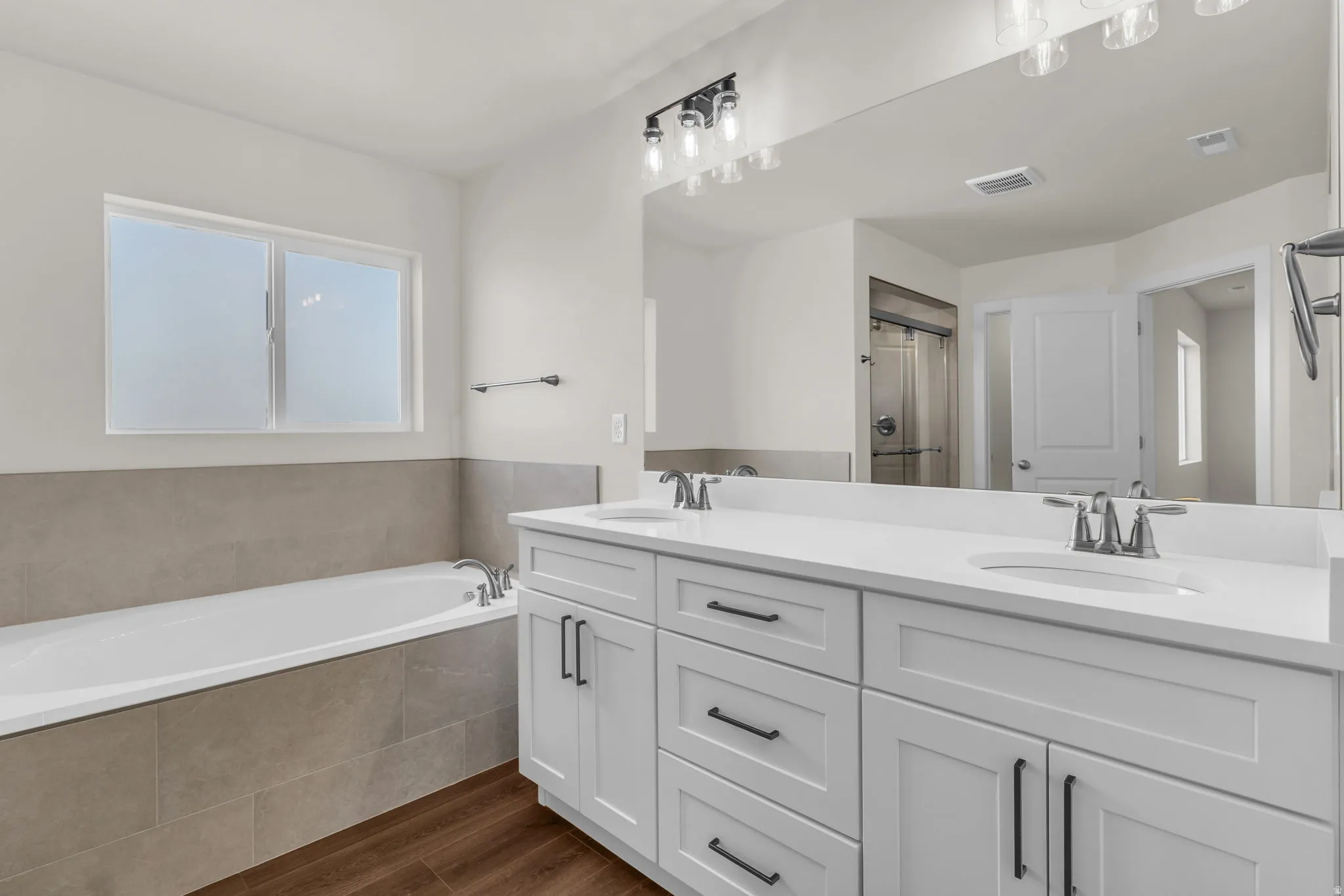 Full bath with dark wood-type flooring, double vanity, a bath, and a shower stall