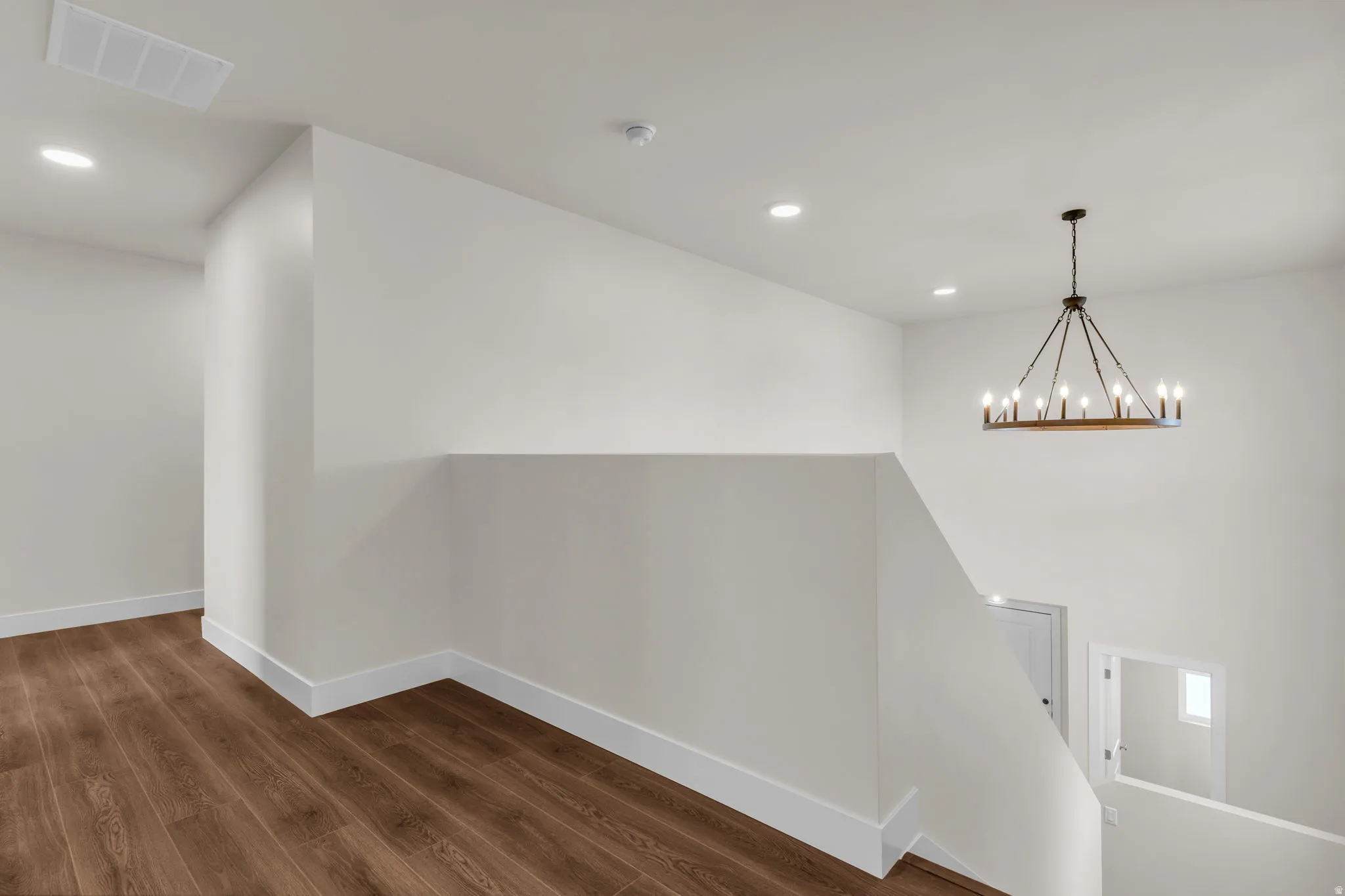 Hallway with dark wood-style floors and a chandelier