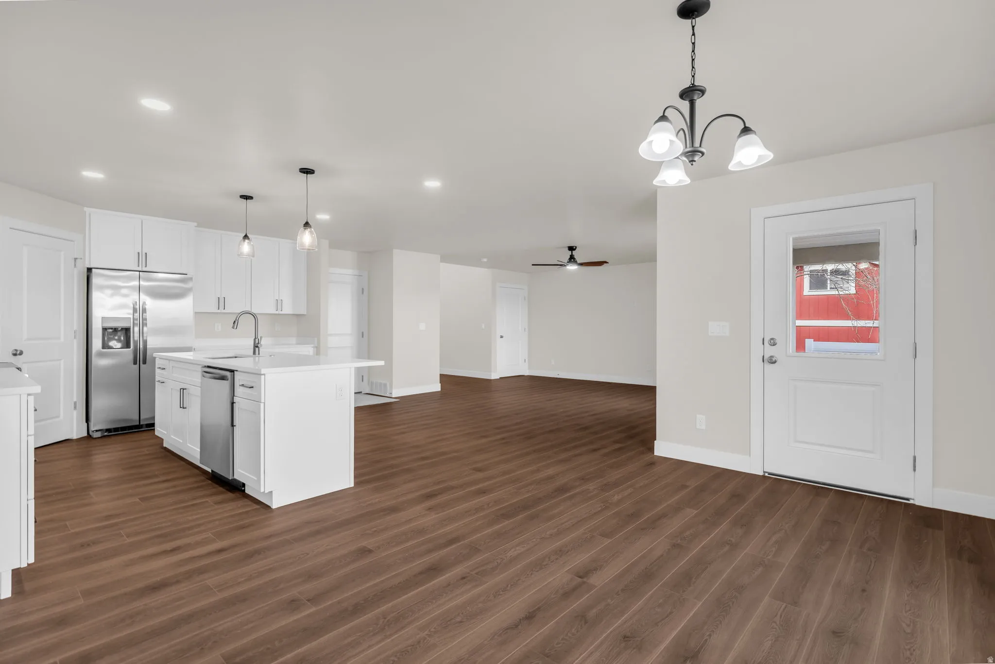 Kitchen featuring ceiling fan, stainless steel appliances, open floor plan, dark wood-type flooring, and white cabinets