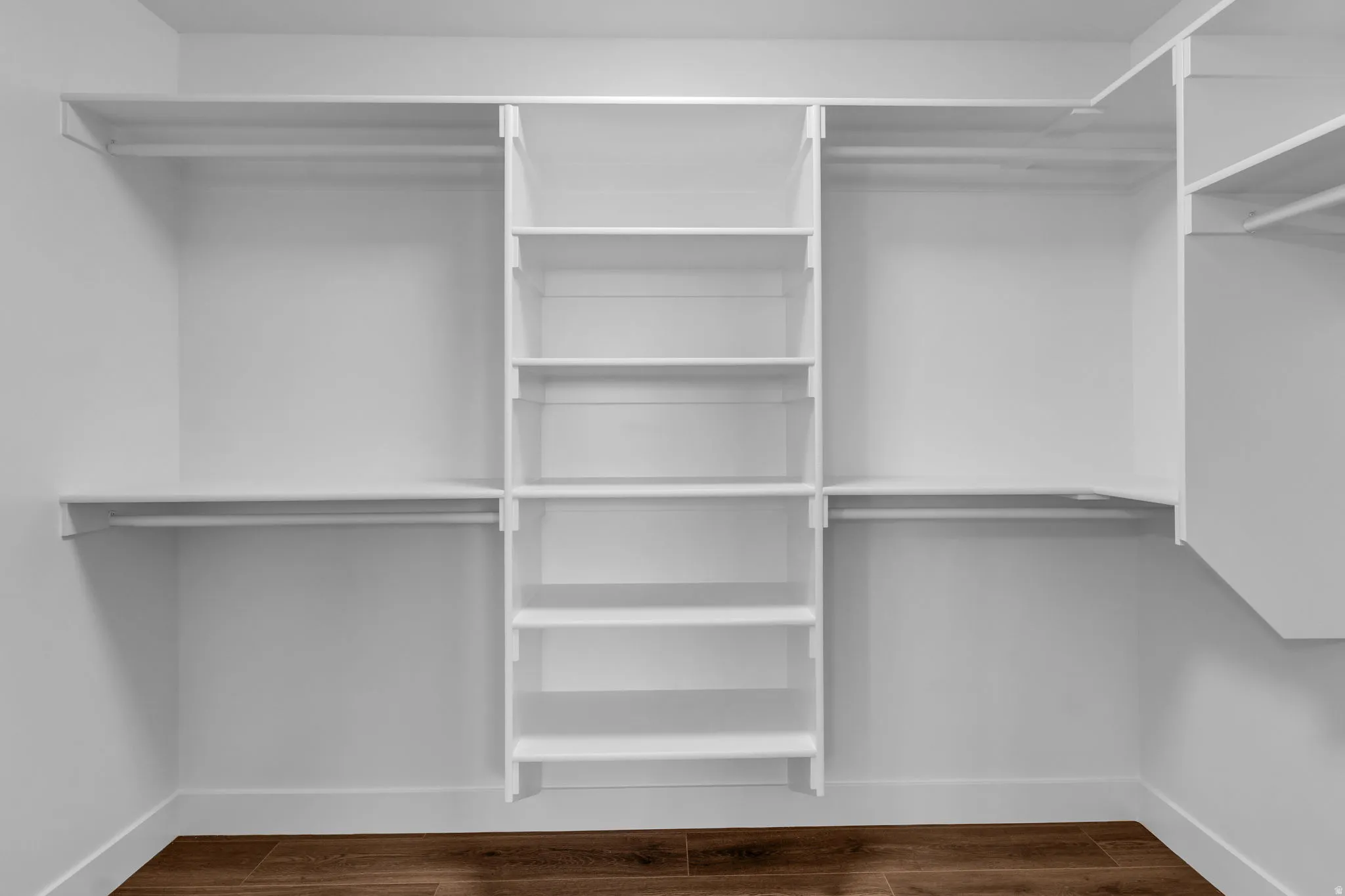 Walk in closet with dark wood-style flooring