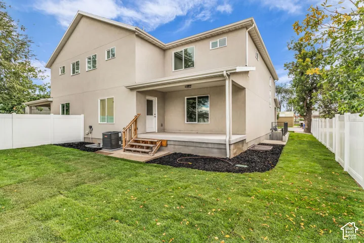 Rear exterior featuring a covered patio, wood stairs, and a white vinyl fence