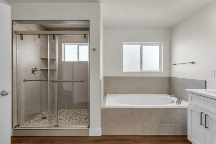 Full bathroom with vanity, a shower stall, a bath, and wood finished floors