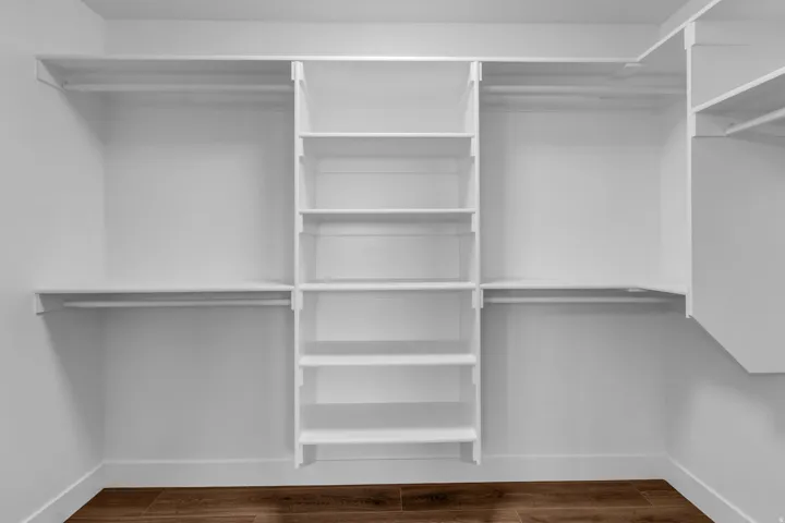 Walk in closet with dark wood-style flooring