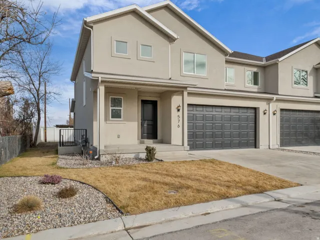 Traditional-style house with covered porch, a garage, stucco siding, and driveway