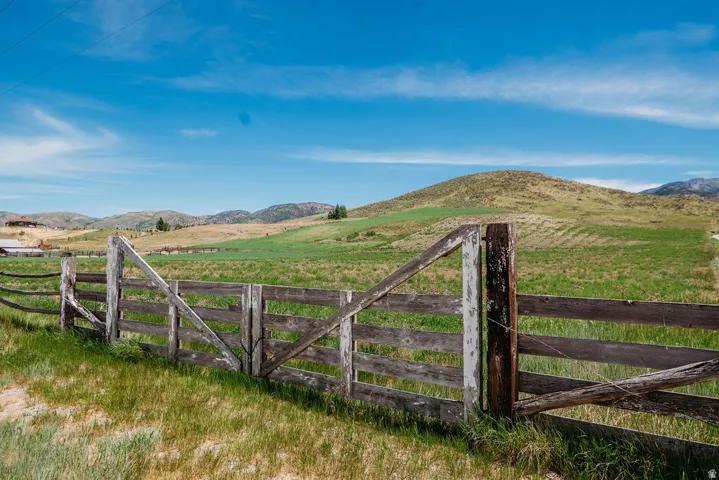 Wood-post perimeter fencing bordering expansive green fields and rolling hills