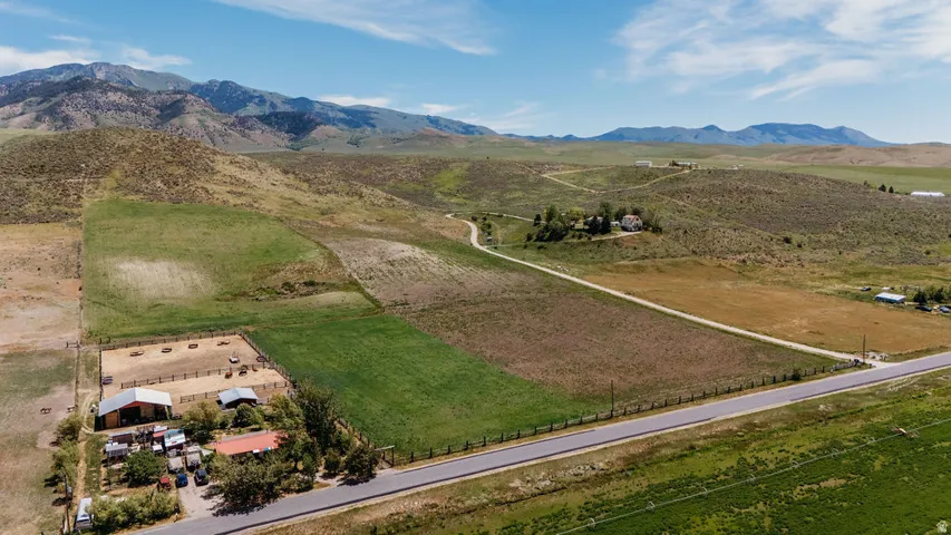 Expansive rural property featuring multiple outbuildings, fenced enclosures, various cultivated and natural land areas, and direct road frontage
