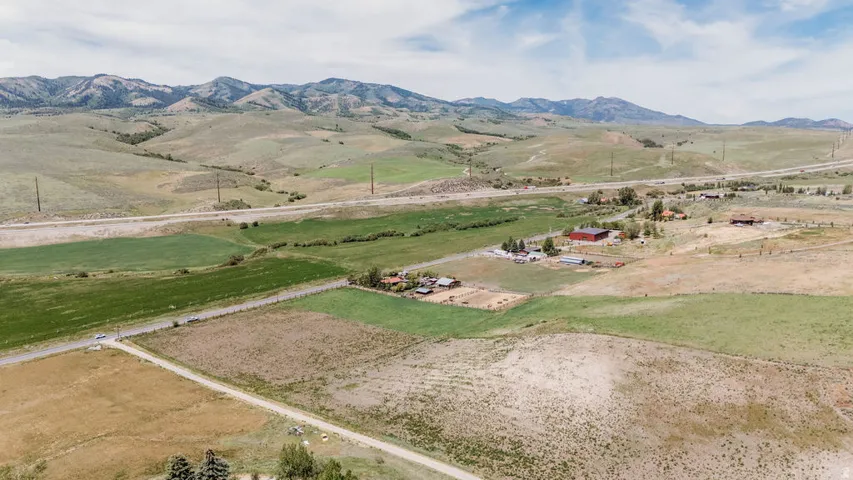 Expansive rural acreage featuring diverse terrain, scattered structures, and mountain scenery