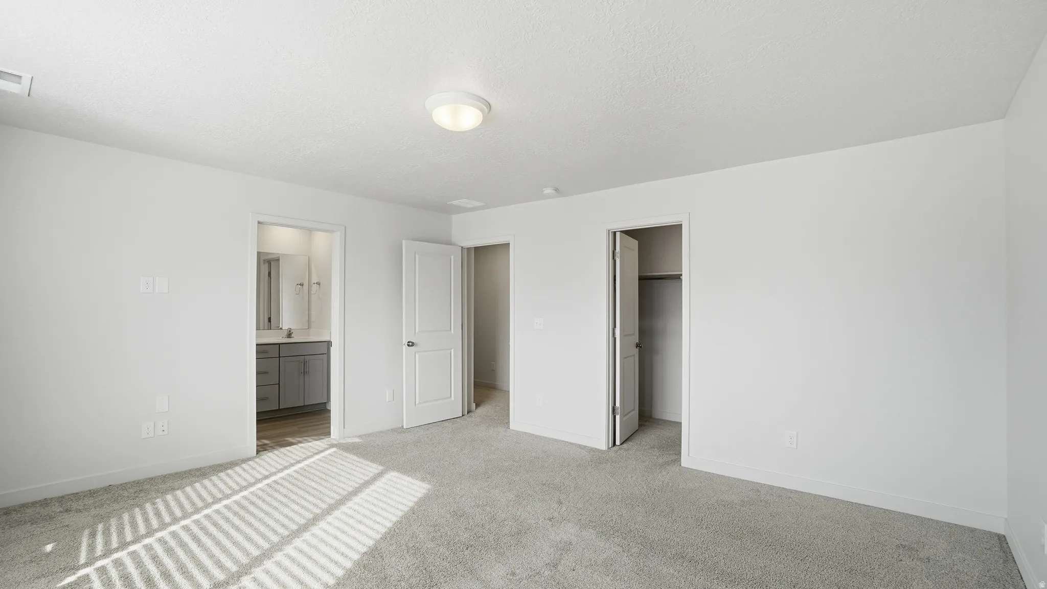 Unfurnished bedroom featuring a walk in closet, carpet, and connected bathroom