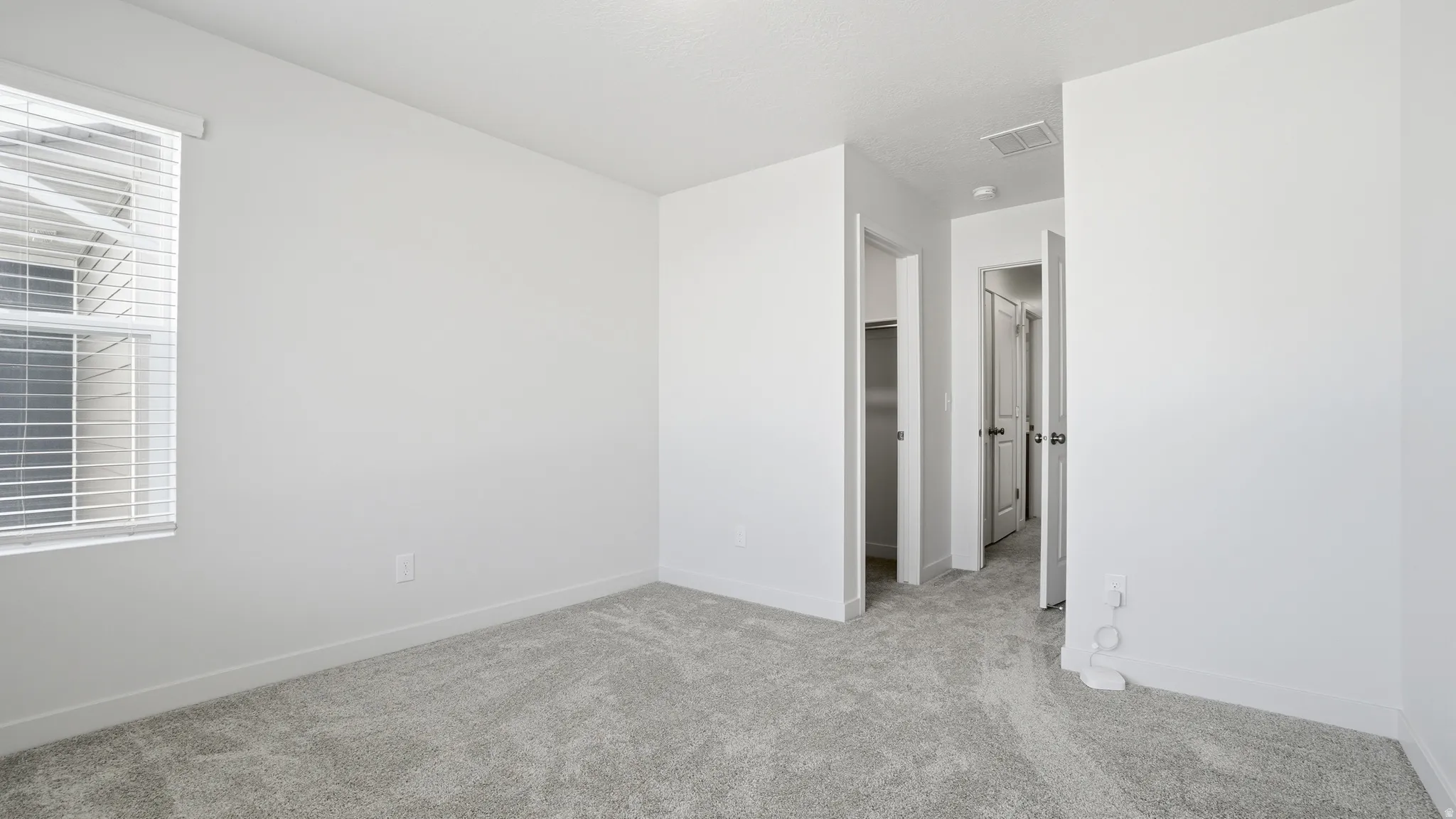 Unfurnished bedroom with a walk in closet and light colored carpet