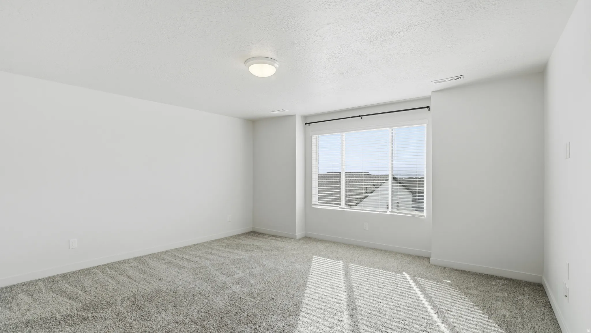 Carpeted empty room with baseboards and a textured ceiling
