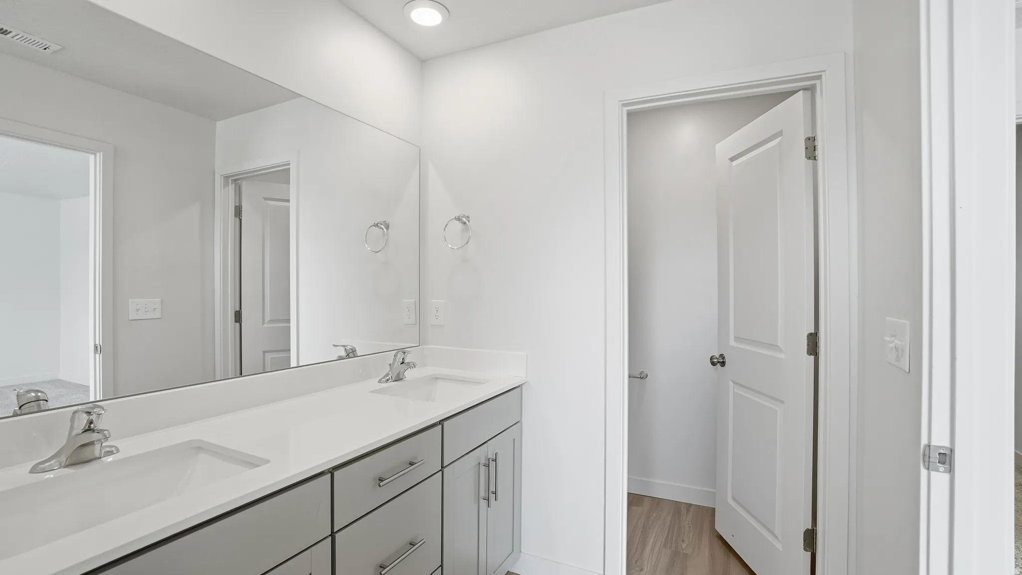 Full bathroom featuring double vanity, light wood finished floors, and recessed lighting