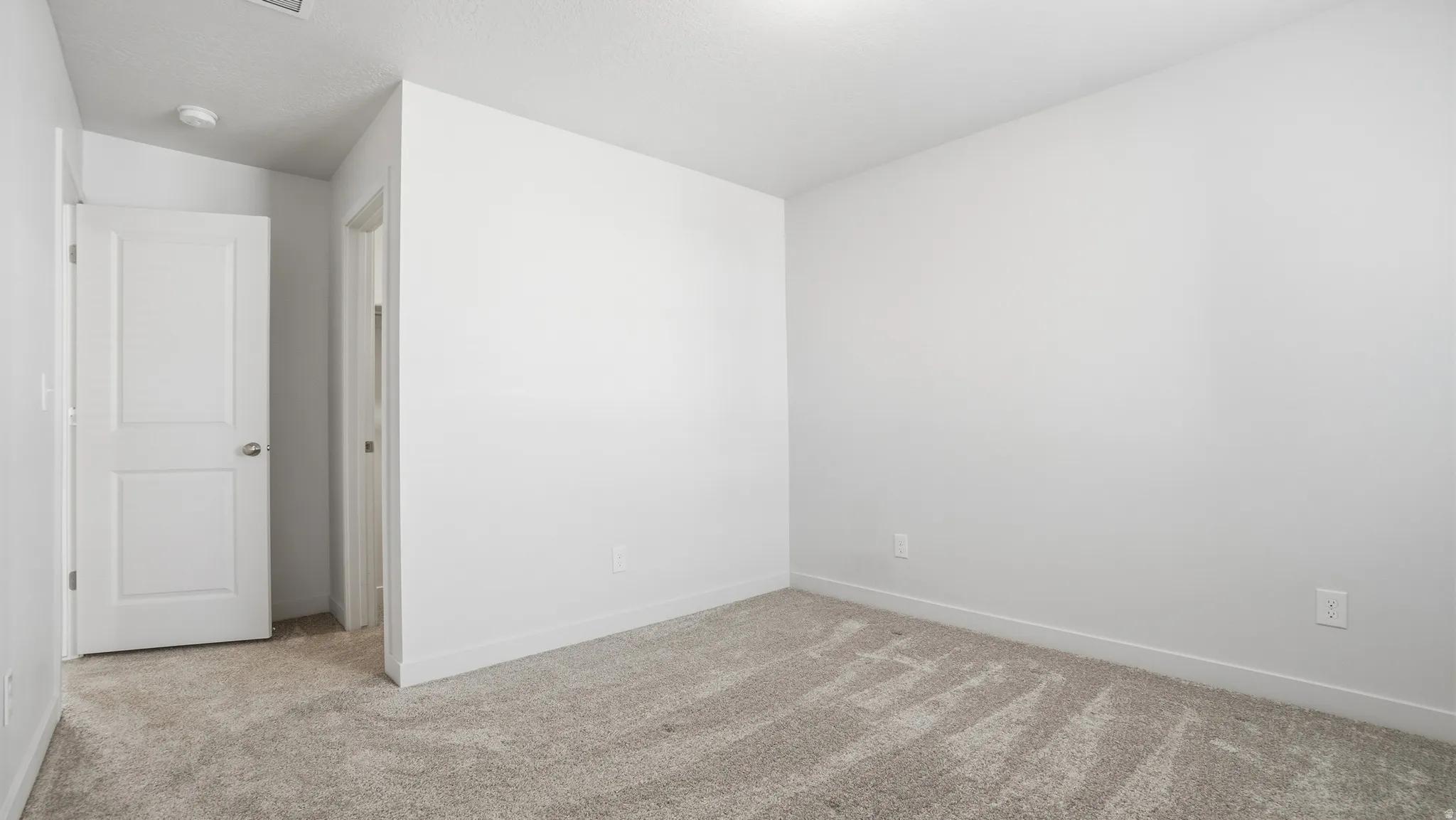 Spare room featuring light carpet and baseboards