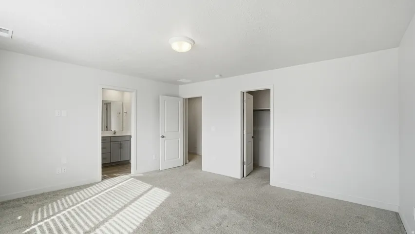 Unfurnished bedroom featuring a walk in closet, carpet, and connected bathroom