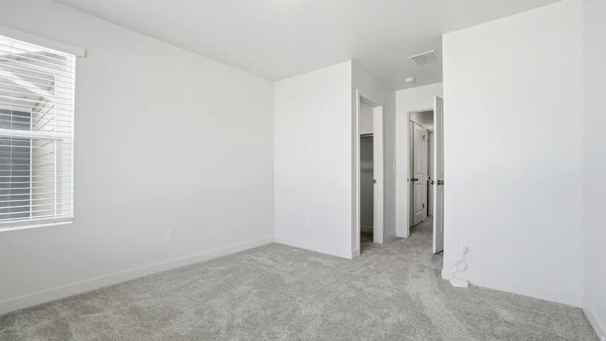 Unfurnished bedroom with a walk in closet and light colored carpet