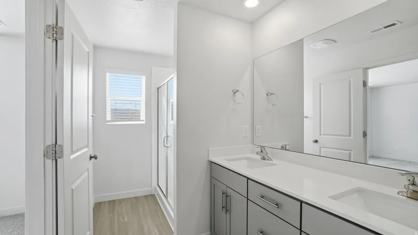 Full bath featuring a stall shower, double vanity, light wood-type flooring, and a textured ceiling