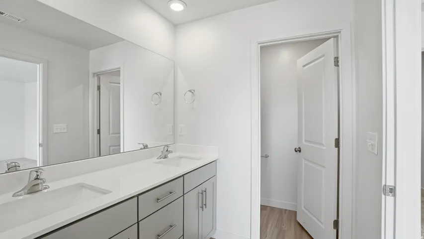 Full bathroom featuring double vanity, light wood finished floors, and recessed lighting