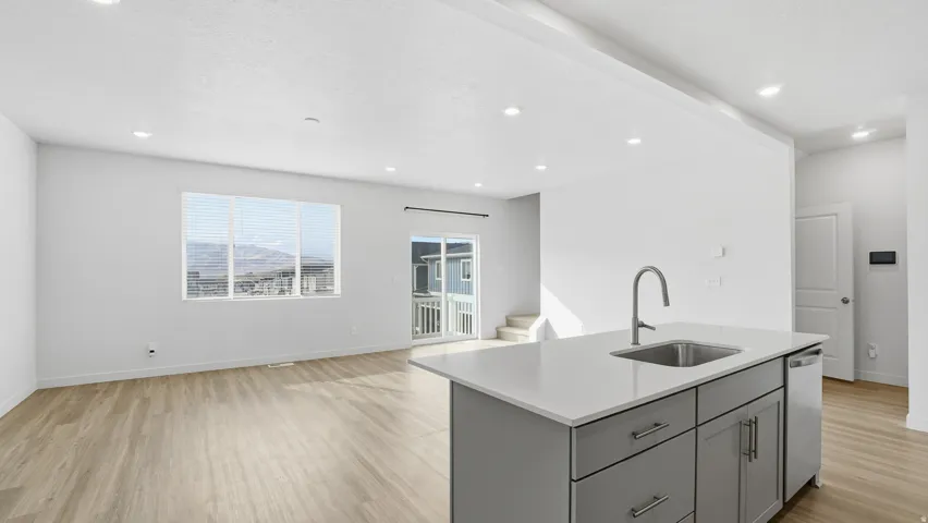 Kitchen featuring gray cabinets, a kitchen island with sink, light wood-type flooring, open floor plan, and recessed lighting